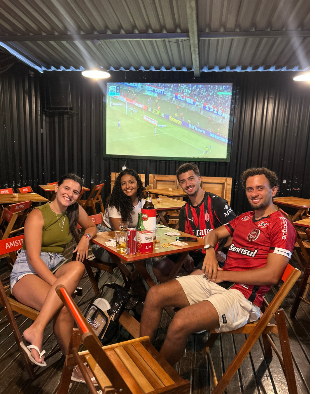 Clientes assistindo ao jogo no telão do Desembarga Bar